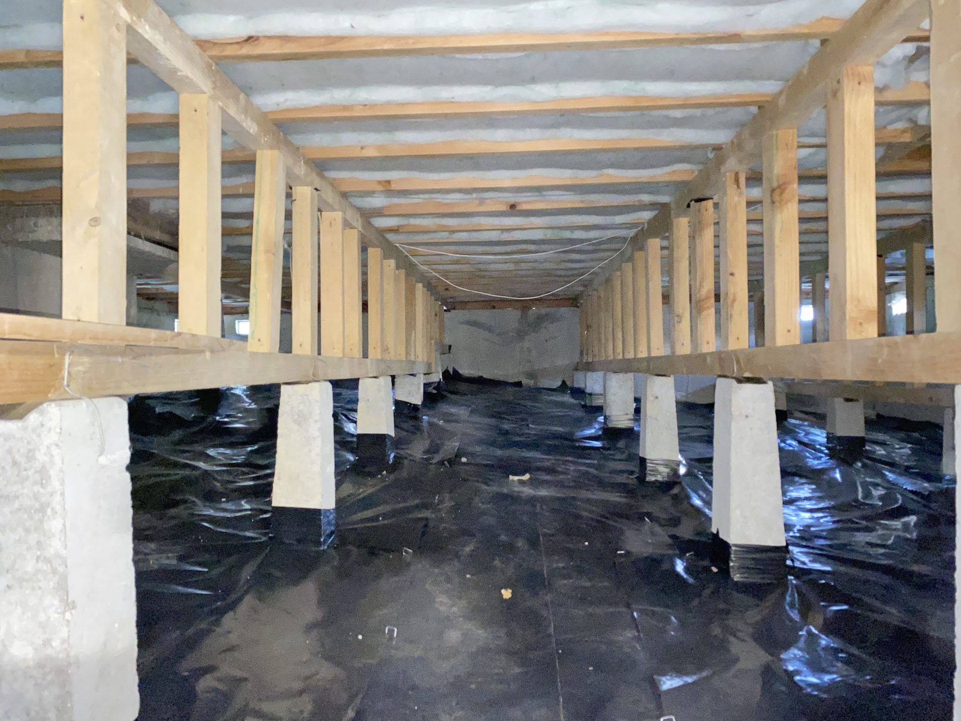 Subfloor with a new ground moisture barrier laid between concrete piles
